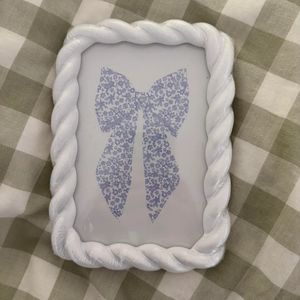 White twisty picture frame with blue bow
photo of...
